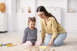 © New Africa - Mother and her daughter playing with toys on floor at home