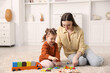 © New Africa - Mother and her daughter playing with toys on floor at home