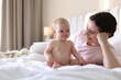 © New Africa - Mother and her cute baby on bed at home. Space for text