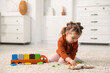 © New Africa - Cute little girl playing with toys on floor at home