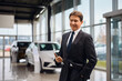 © Drazen - Experienced car salesman in showroom looking at camera.