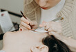 © Nataliya - Portrait of a girl cosmetologist extending eyelashes to a woman.