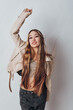 © SHOTPRIME STUDIO - Young woman with long hair wearing casual jacket and crop top posing with raised arm in studio. Smiling female model in trendy outfit with relaxed confident expression and dynamic hairstyle.