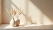 © Pete - Two minimal ceramic vases hold pampas grass on shelf. Natural light casts soft shadows on neutral wall creating calm mood for home decor interiors.