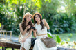 © apichat - Asian women friends enjoying summer vacation outdoors with smartphone