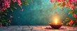 © Maryna - Oil lamp with lit wick glows near pink blossoms and green leaves. Stone path carpeted with flower petals forms festive Indian scene. Space for copy on tranquil background.