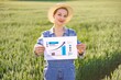 © sofiko14 - A woman in overalls and a straw hat stands in a green field holding a paper with a bar graph and an upward trending arrow indicating growth