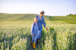 © sofiko14 - A woman and a young girl walk through a lush green wheat field under a clear sky, showcasing a connection to nature and agriculture