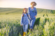 © sofiko14 - A mother and her daughter walk hand-in-hand through a golden wheat field at sunset, enjoying a peaceful moment together