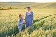 © sofiko14 - A mother and her young daughter holding hands while walking through a golden wheat field at sunset, enjoying a peaceful moment together