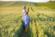 © sofiko14 - A mother and her young daughter walk through a lush green wheat field, enjoying a sunny day outdoors
