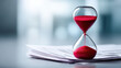 © javu - Red hourglass on paperwork symbolizes deadlines time passing tariffs in business planning