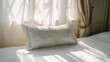 © Big - Hotel bed with crisp white linens and decorative pillow in soft morning light through sheer curtains.