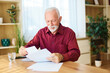 © Lumos sp - Portrait of a mature senior man a businessman working from home signing a document or an agreement, home office, or a student learning, or mature man writing and reading