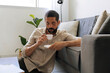 © kleberpicui - Adult man enjoying coffee while reading book at home. Quiet break moment highlighting relaxation, focus and balanced lifestyle inside bright modern living room.