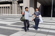 © wavebreak3 - Diverse male friends walking across tiled plaza near concrete building holding football and duffel