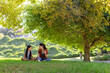 © Wavebreak Media - Mother gesturing and teaching daughter on lawn under tree, animated light highlighting education