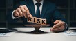 © Afsana - Businessman assessing risk with wooden blocks on a scale