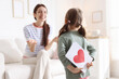 © New Africa - Happy Mother's Day. Little girl surprising her mom with holiday card indoors, selective focus