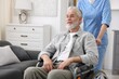© New Africa - Care worker with senior man in wheelchair indoors, closeup