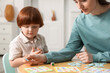 © New Africa - Mother and her son playing with toys at wooden table indoors
