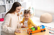 © New Africa - Mother and her daughter playing with toys at wooden table indoors