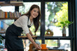 © apichat - Smiling woman serving coffee in cozy cafe
