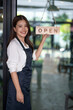© apichat - Young woman owner opening small business storefront