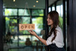 © apichat - Business owner changing open sign on glass door