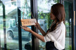 © apichat - Woman hanging closed sign on storefront door
