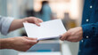 © Puthorn - Close up of a man's hands passing a stack of blank white papers or documents to another person in an office environment.