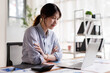 © David - Confident Young Asian Businesswoman Sitting at Desk with Laptop and Financial Documents in Modern Office