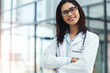 © peopleimages.com - Happy woman, portrait and doctor with confidence for healthcare or medical service in hospital. Female person, cardiologist or professional health worker with smile or arms crossed for care on space