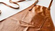 © Gelas - Stylish leather apron with front pocket and brown straps against a white backdrop