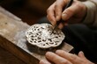 © zhang yongxin - Artisan crafting intricate metalwork with a precision tool on a wooden workbench