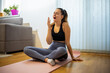 © Mediteraneo - Tired young woman in sportswear yawning while sitting on a yoga mat at home.