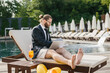 © dsheremeta - Businessman working on laptop by the pool