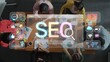 © InfiniteFlow - A diverse team collaborates on SEO strategies at a modern workspace, utilizing digital tools and infographics to enhance online performance and marketing insights. Raster