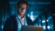 © Drion - A focused man working on his laptop in a dimly lit server room at night