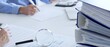 © rogerphoto - Professional colleagues reviewing financial reports, examining graphs and documents with magnifying glass, laptop on minimalist white workspace. Audit and taxes in business