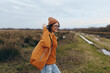 © SHOTPRIME STUDIO - Young woman lifestyle in casual autumn clothes walking on rural path. She wears orange jacket and hat, smiling with glasses in natural outdoor environment. Concept of freedom and nature.