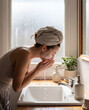 © Restu - Woman Washing Face in Bathroom Sink During Morning Skincare Routine with Natural Window Light