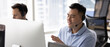 © fizkes - Customer service department. Wide panoramic image confident young man hotline operator helpdesk technician in headset contact client with friendly smile give live assistance support by computer screen