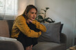 © PRIME STOCK LAB - Sad woman sitting on sofa feeling lonely suffering from depression at home looking stressed with anxiety while hugging knees inside room