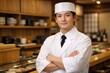 © Jumpei - 腕組みをして清潔感のある白い調理服を着た笑顔の若板前が立ち並ぶ寿司屋のカウンター内側