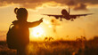 © Alexey - Silhouetted young girl with a backpack pointing at a flying airplane during a golden sunset for travel adventure concept and future dreams
