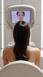 © PhotoLuxeStudio - woman with long dark hair undergoing facial skin analysis with advanced digital device in clinic