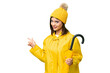 © luismolinero - Young Russian woman with rainproof coat and umbrella over isolated chroma key background pointing back