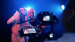 © DMegias - Musicians singing into a microphone on a studio set, filming a music video under dramatic blue and red lighting, confident performers