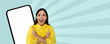 © Prostock-studio - A person stands happily, pointing at a blank phone screen. The background shows some bright colors and patterns. This scene is meant for showcasing digital content or marketing.